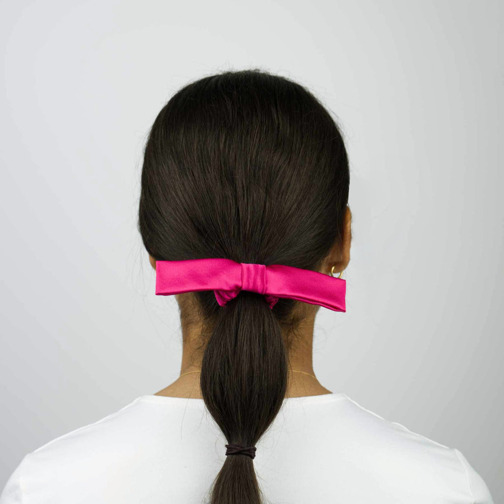 Le chouchou à nœud en soie rose fuchsia sublime vos cheveux. Fait main en France à partir de tissus de maisons du groupe LVMH. Édition limitée.